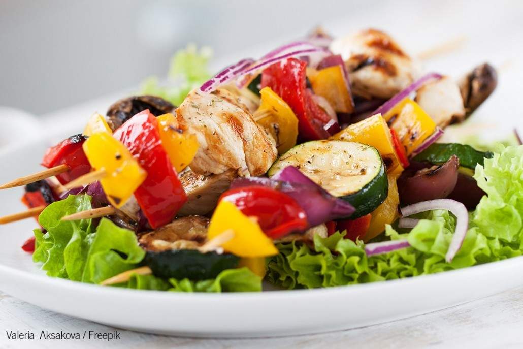 Kebab- Closeup of chicken skewers or shashlik with grilled vegetables (mushrooms, paprika, salad, zucchini, onion)