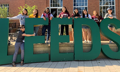 students standing in front of leeds letters