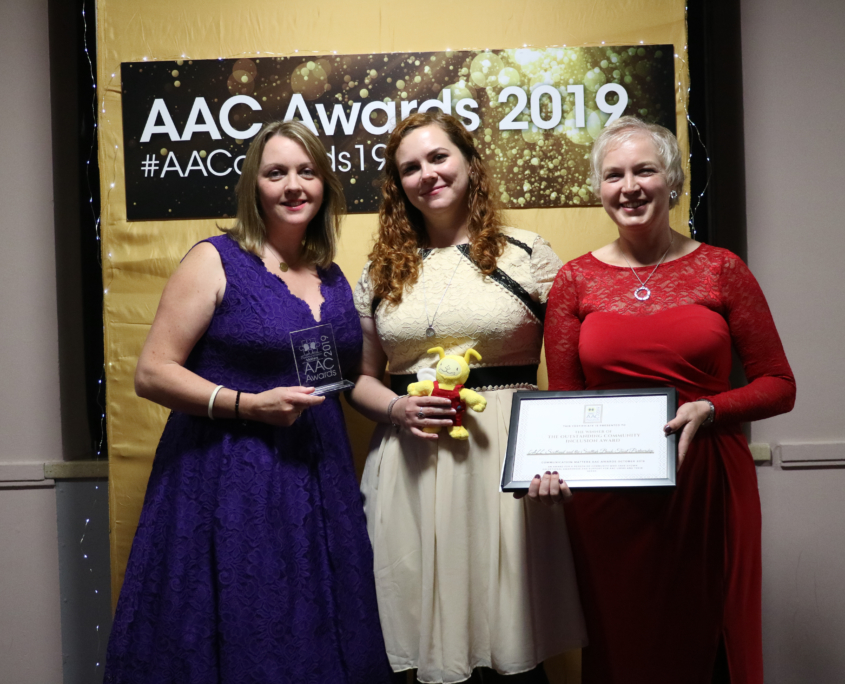 Three women standing with an award