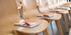 Row of chairs with notepads and pens