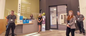 5 people standing in reception wearing face masks